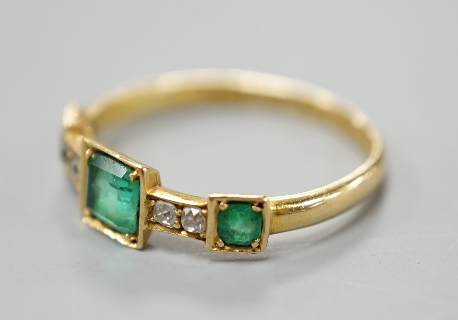 A George V 18ct gold, three stone emerald and four stone diamond chip set half hoop ring, size L, gross weight 1.8 grams.